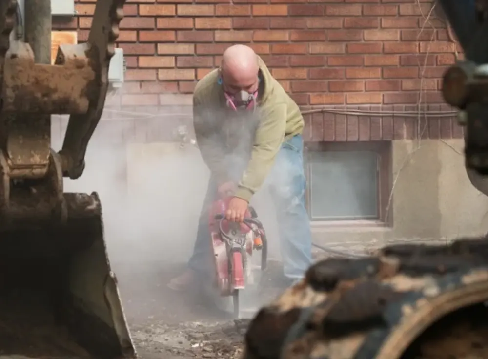 Plumber cutting concrete with a saw for a sewer repair
