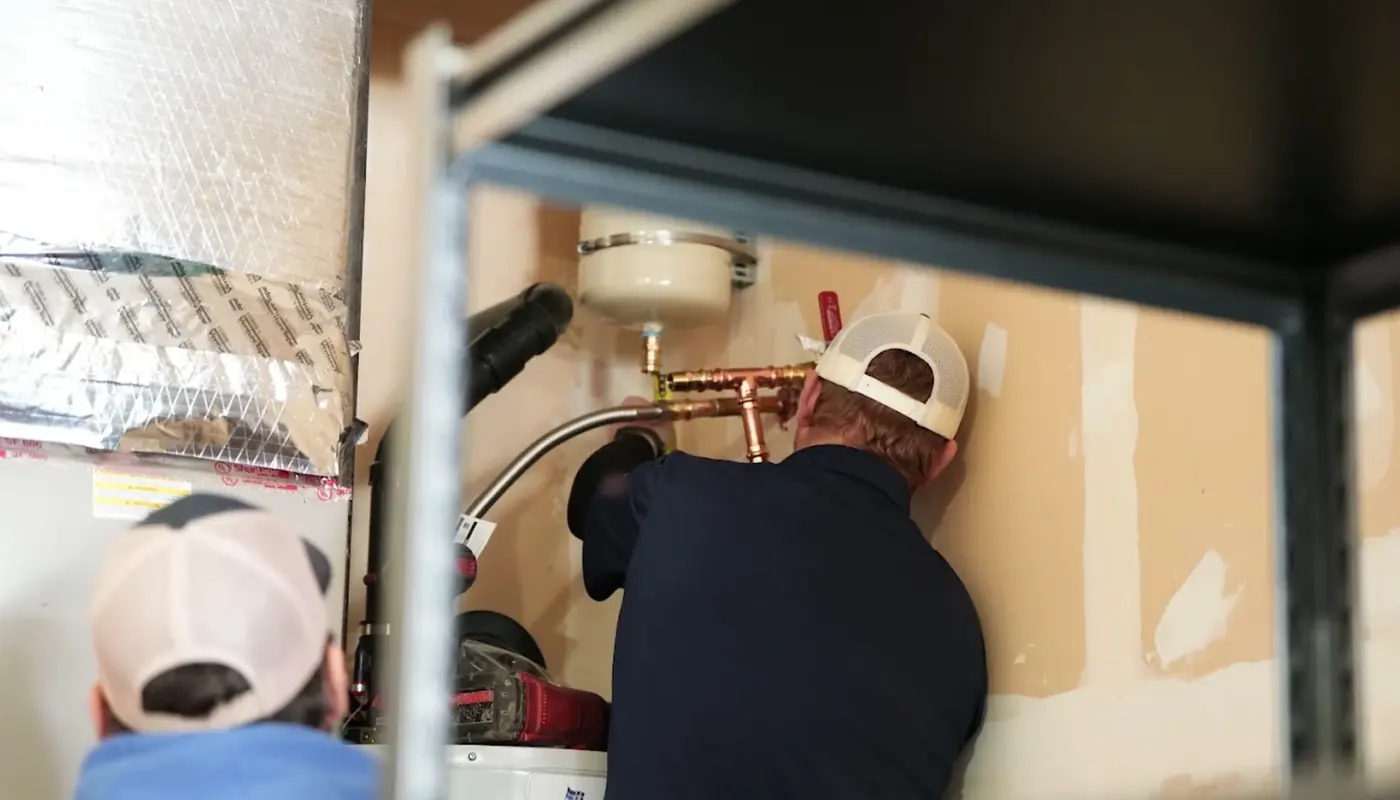 Plumber fitting new copper piping above a water heater