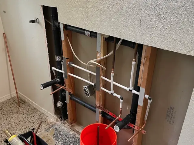 Opened wall showing new water lines and drain piping